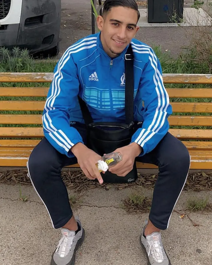 Homme torse nu, aux cheveux bruns, posant dans une lumière vive, regard intense.