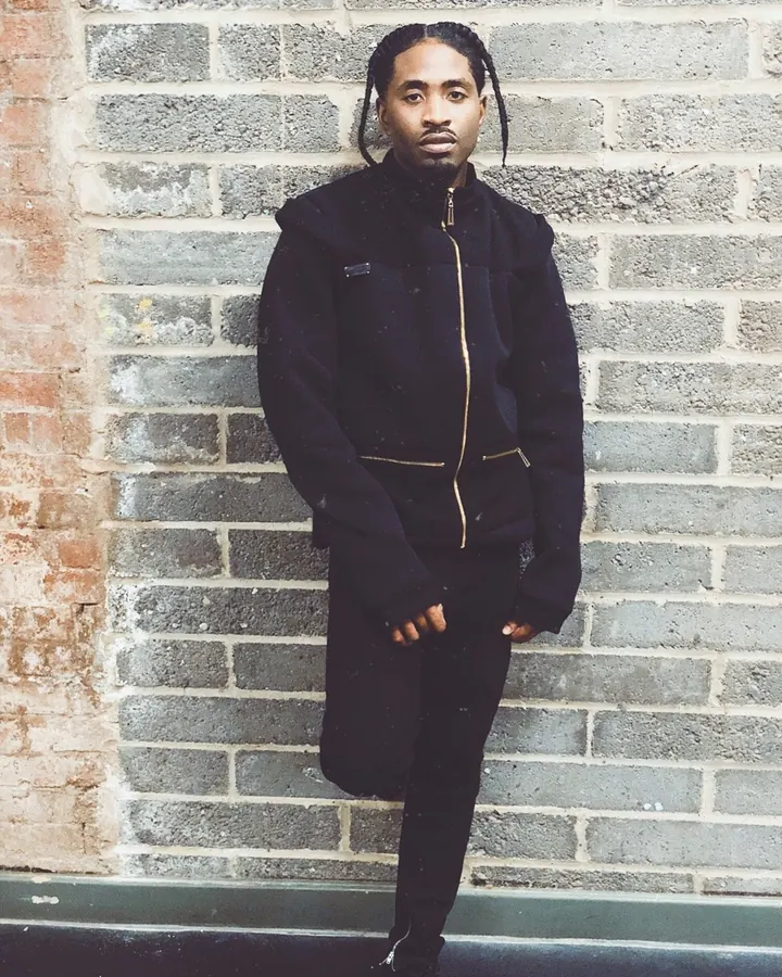 Homme torse nu, cheveux bruns, regardant directement l'objectif, dans un cadre sombre