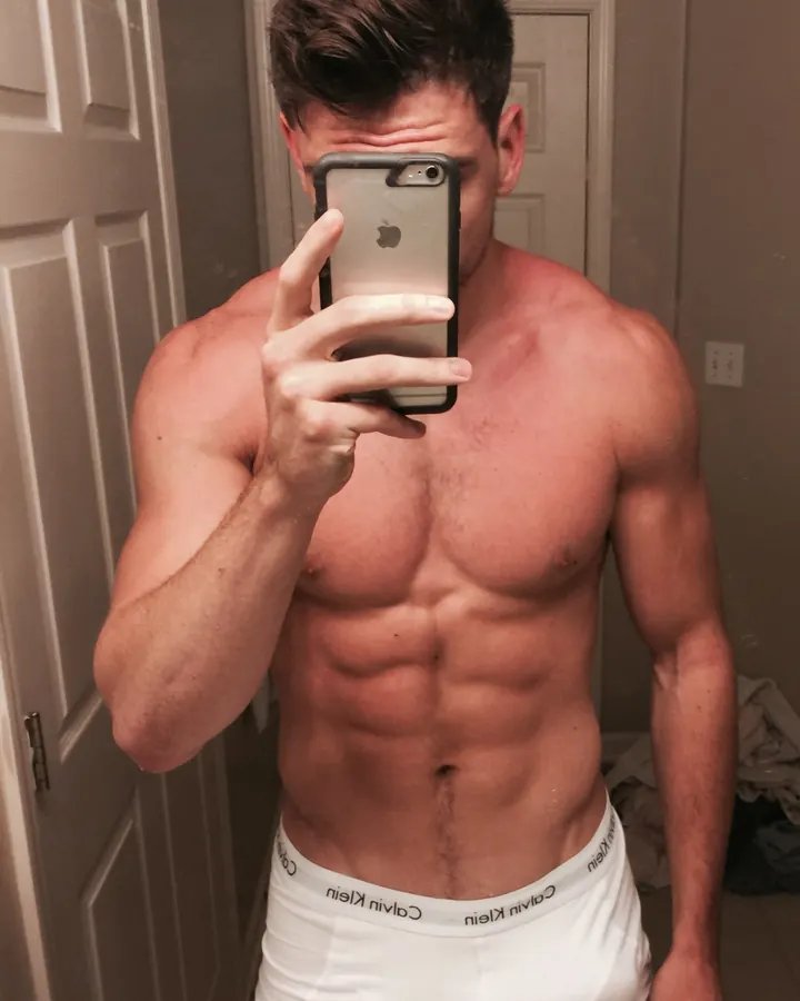 Homme européen torse nu, prenant un selfie dans un miroir, sous-lumière naturelle